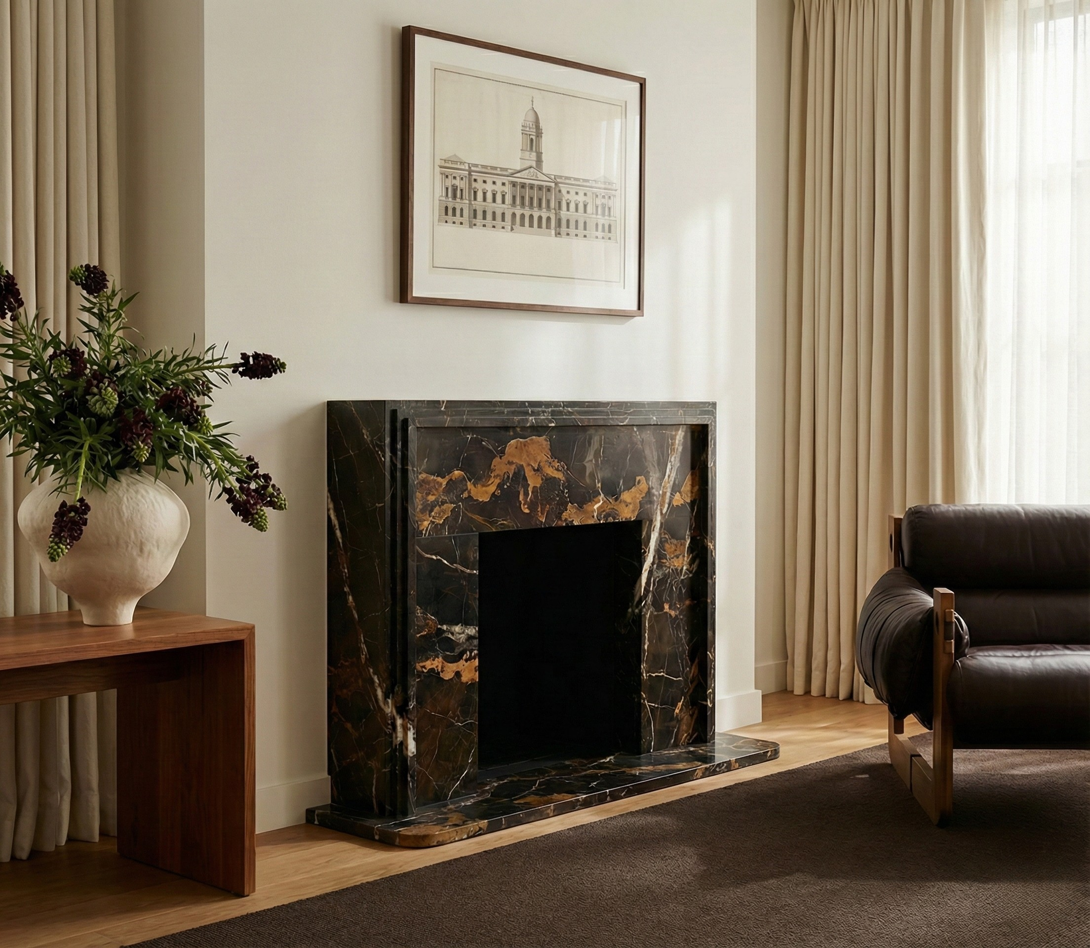 Living room with a marble fireplace, dark sofa, and framed artwork.